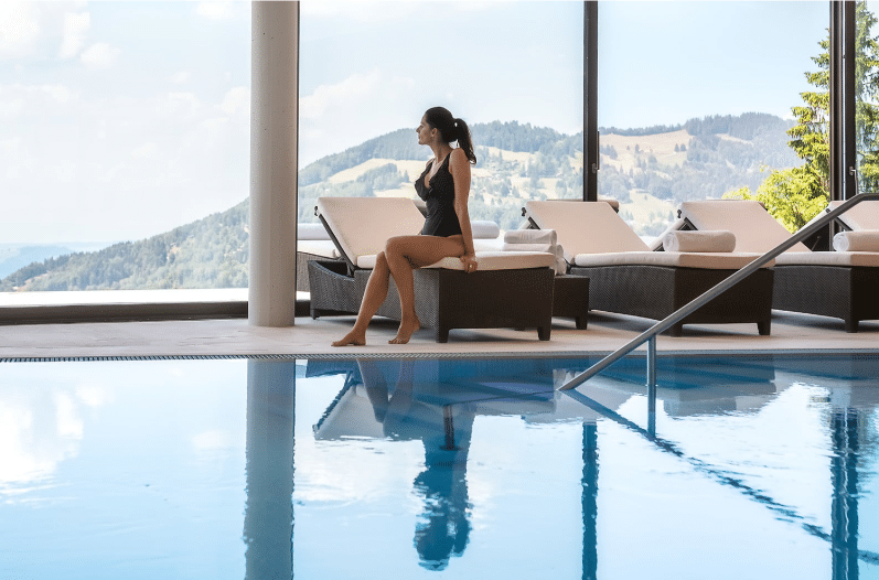 a woman sitting on a chair by a pool