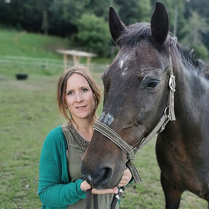 a woman standing next to a horse
