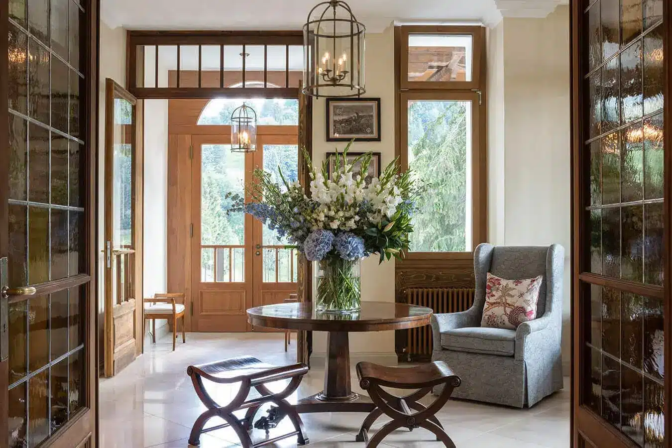 a vase of flowers on a table in a room with chairs and a lamp