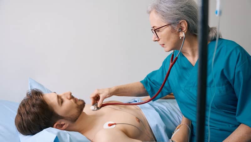 Experienced elderly doctor listens with a stethoscope to young patient