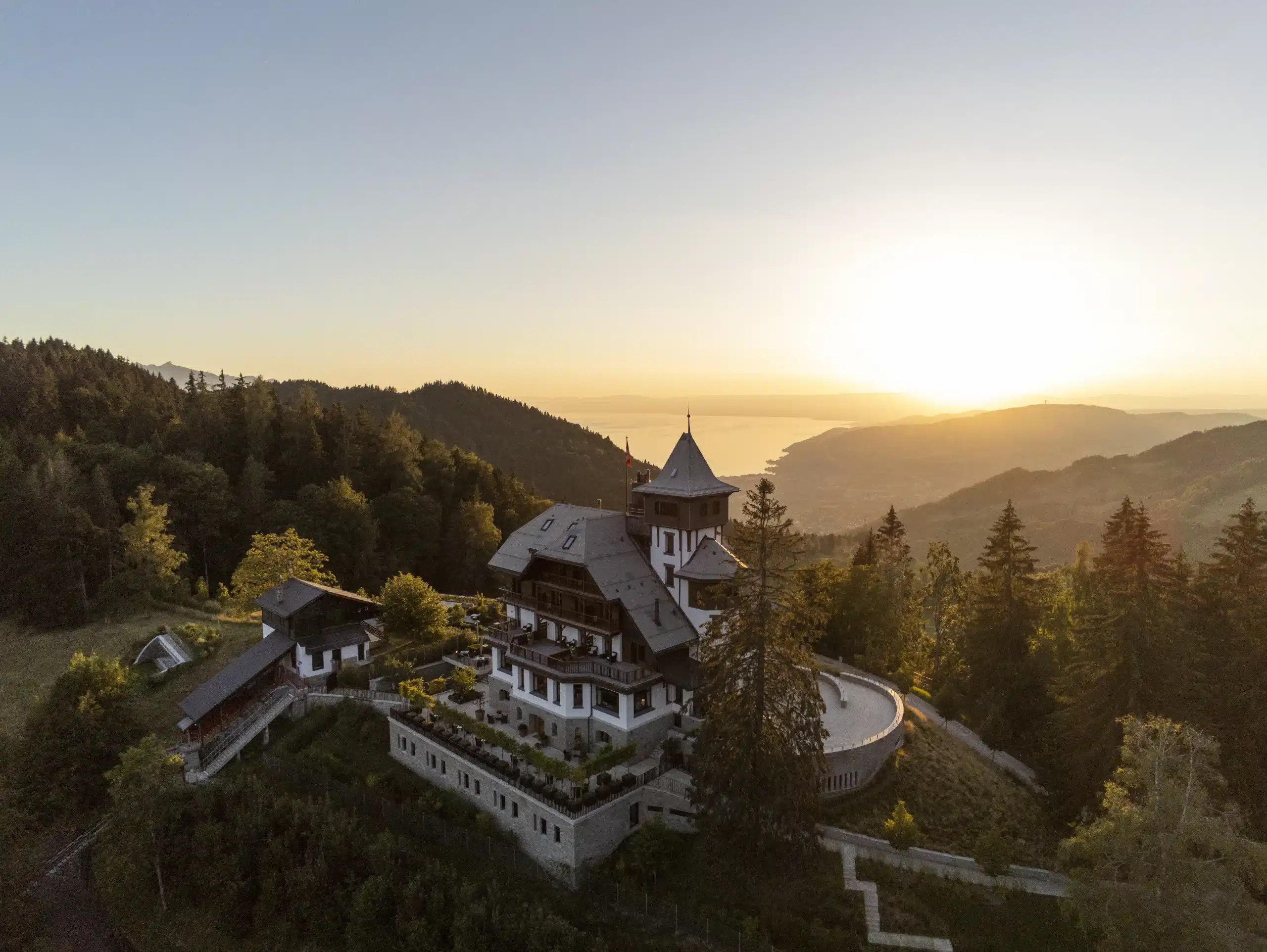 a building with trees and mountains in the background