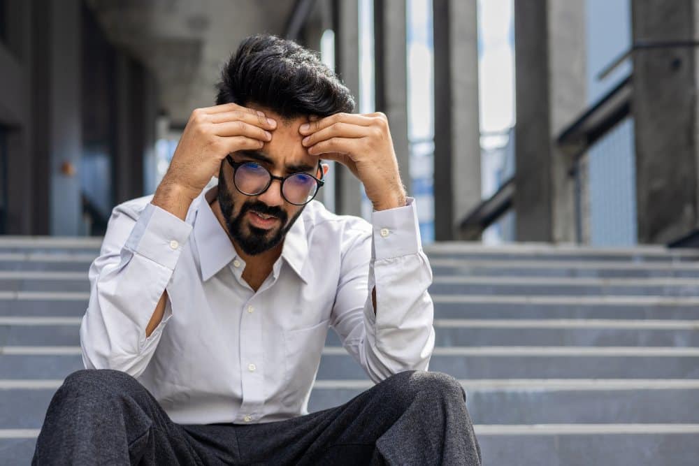 disappointed young man sits on the steps of a business center