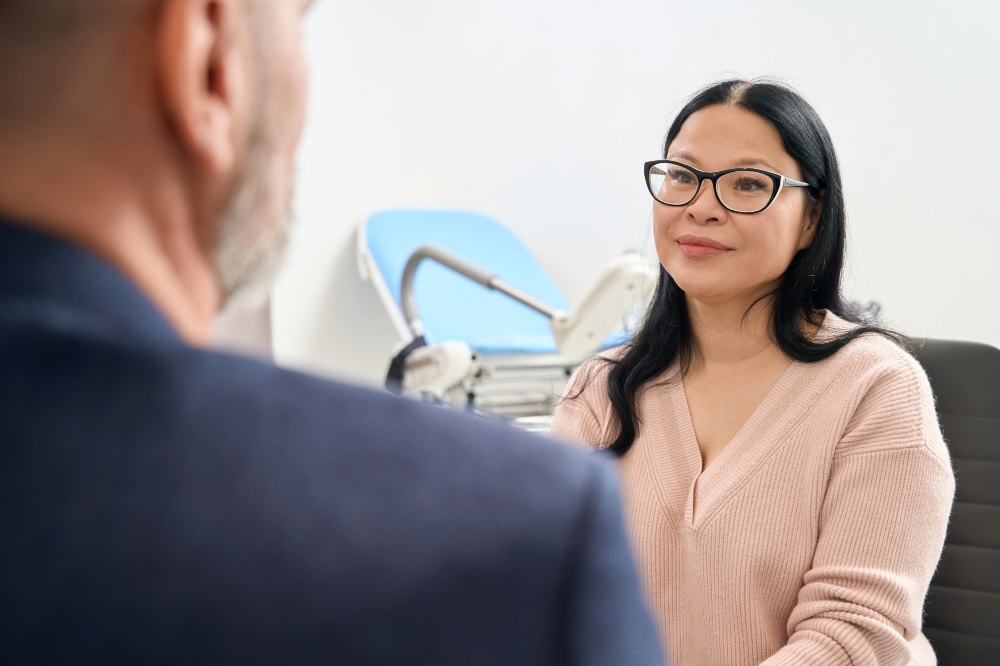 woman in eyeglasses speaking with professional in a clinical setting